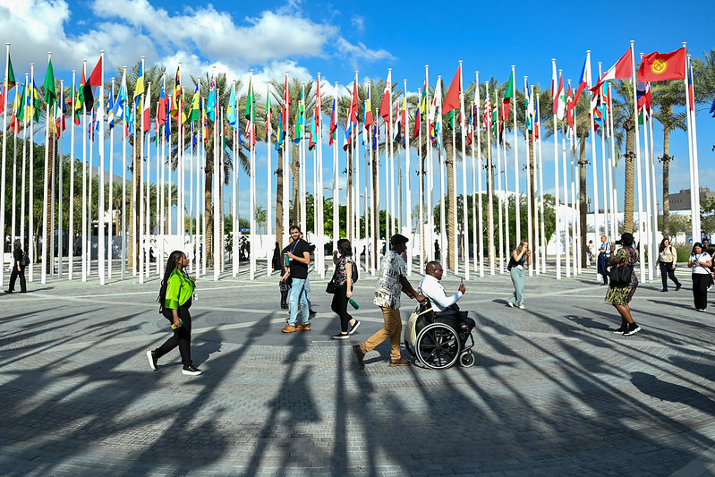 Delegates walk past country flags at COP28