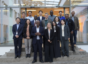 A group of negotiators from regions across the world standing on the stairs of a brightly lit building