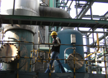 Man in hard hat walks through industrial plant for nitric acid production