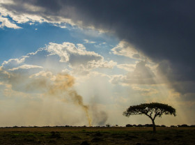 Rainclouds and fire over landscape in Zambia, Africa.