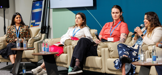 Panelists, one speaking and smiling into microphone